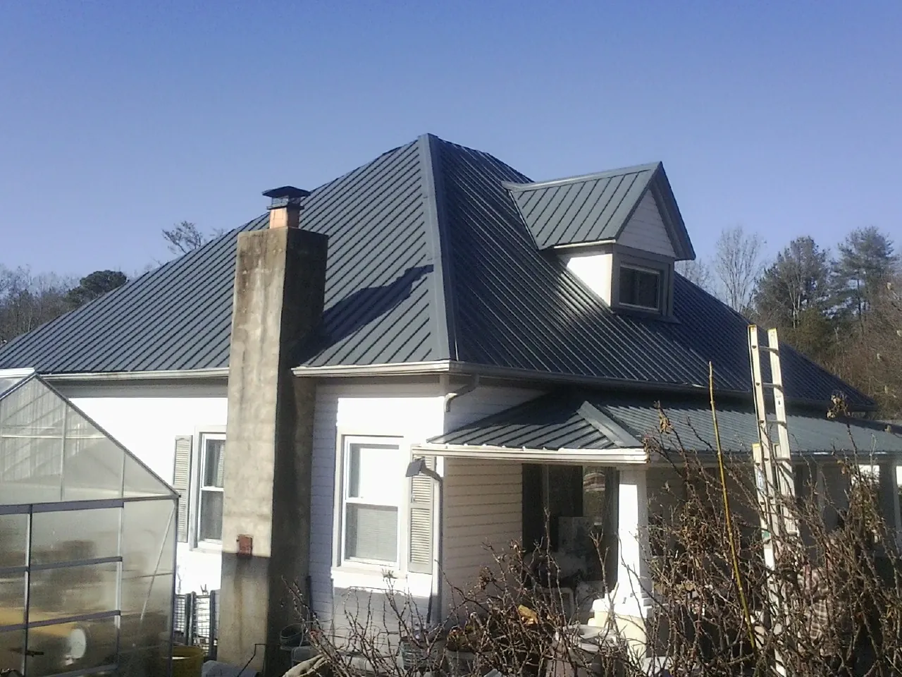 Dark blue standing seam metal roof on a white farmhouse with dormer — Slate & Tile Roof Repair by Roofing Brothers in Paton