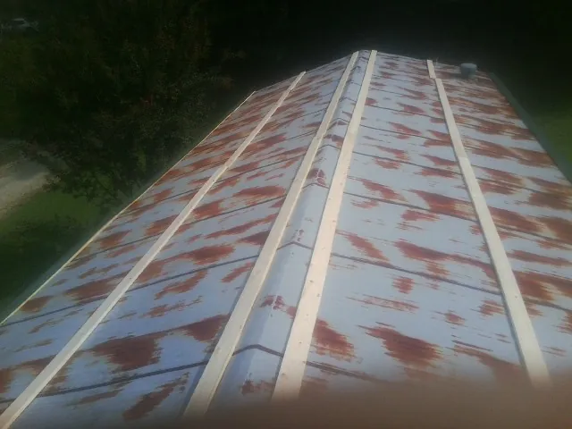 Rusted metal roof panels with new wood purlins before replacement in Paton