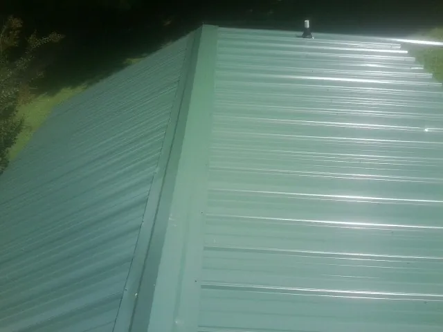 New green metal panels meeting at the ridge of a roof — Flat Roof Repair work by our crew in Paton