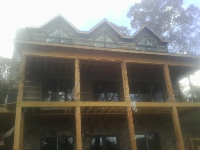 Dormers and porch framing on a large log home under construction — Roof Coating work by our crew in Paton
