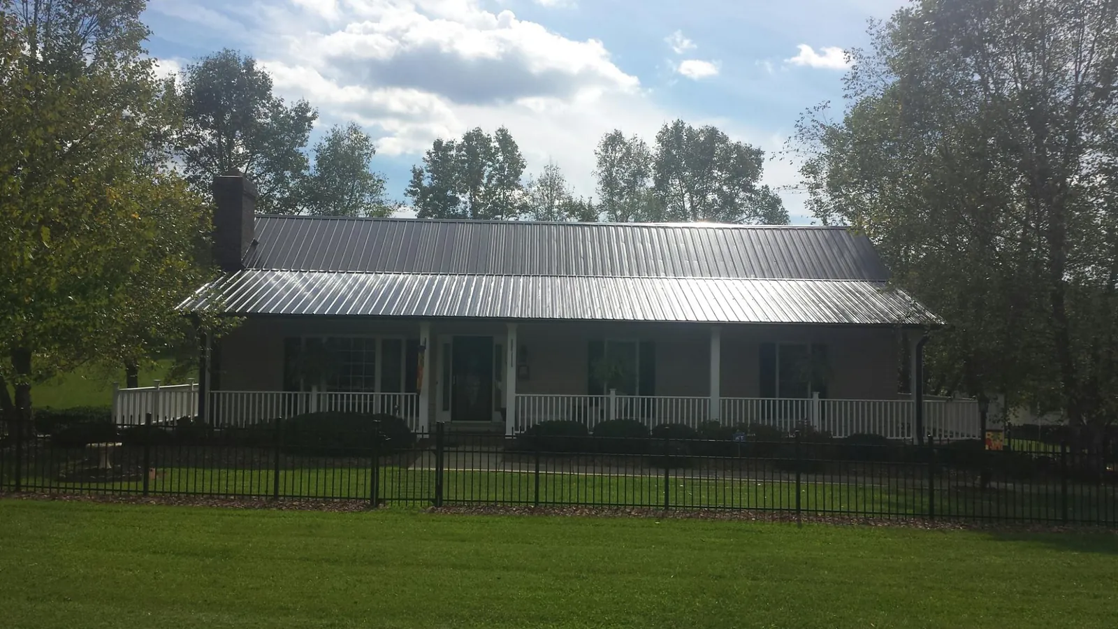 Gray metal roof on a brick ranch with a full width front porch — Gutter Guard Installation work by our crew in Paton