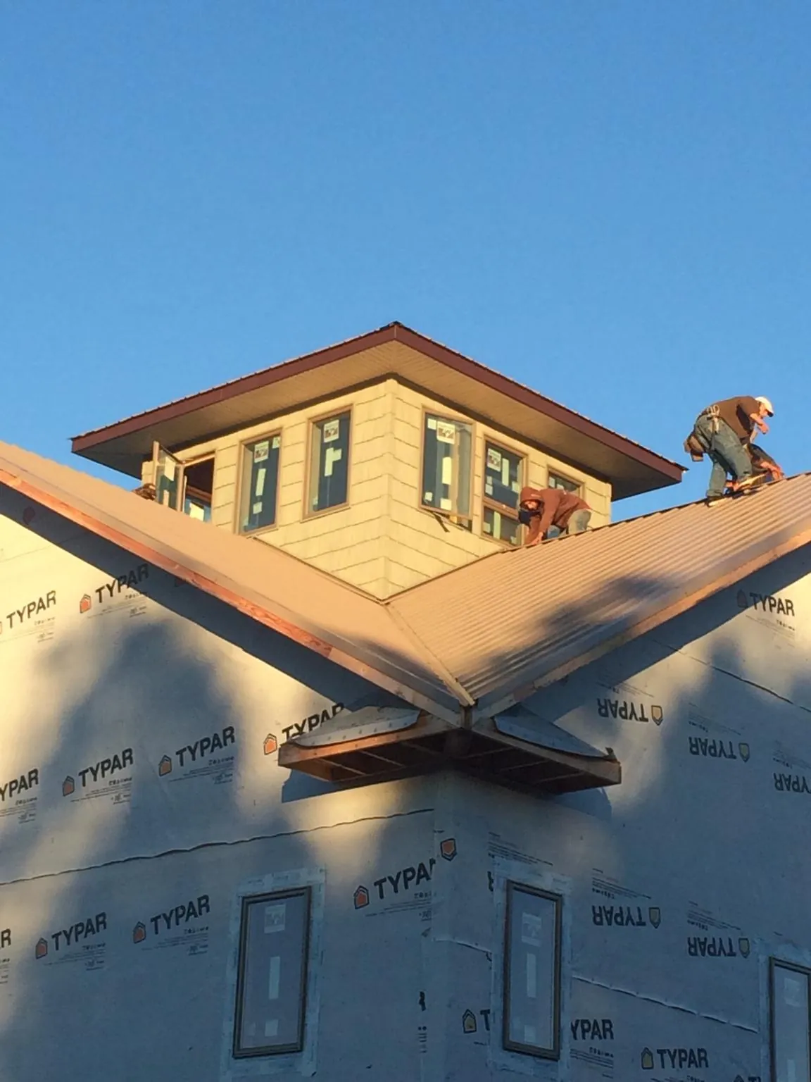 Roofers working around a rooftop cupola on a new metal roof at sunset — Roof Waterproofing in Paton by Roofing Brothers